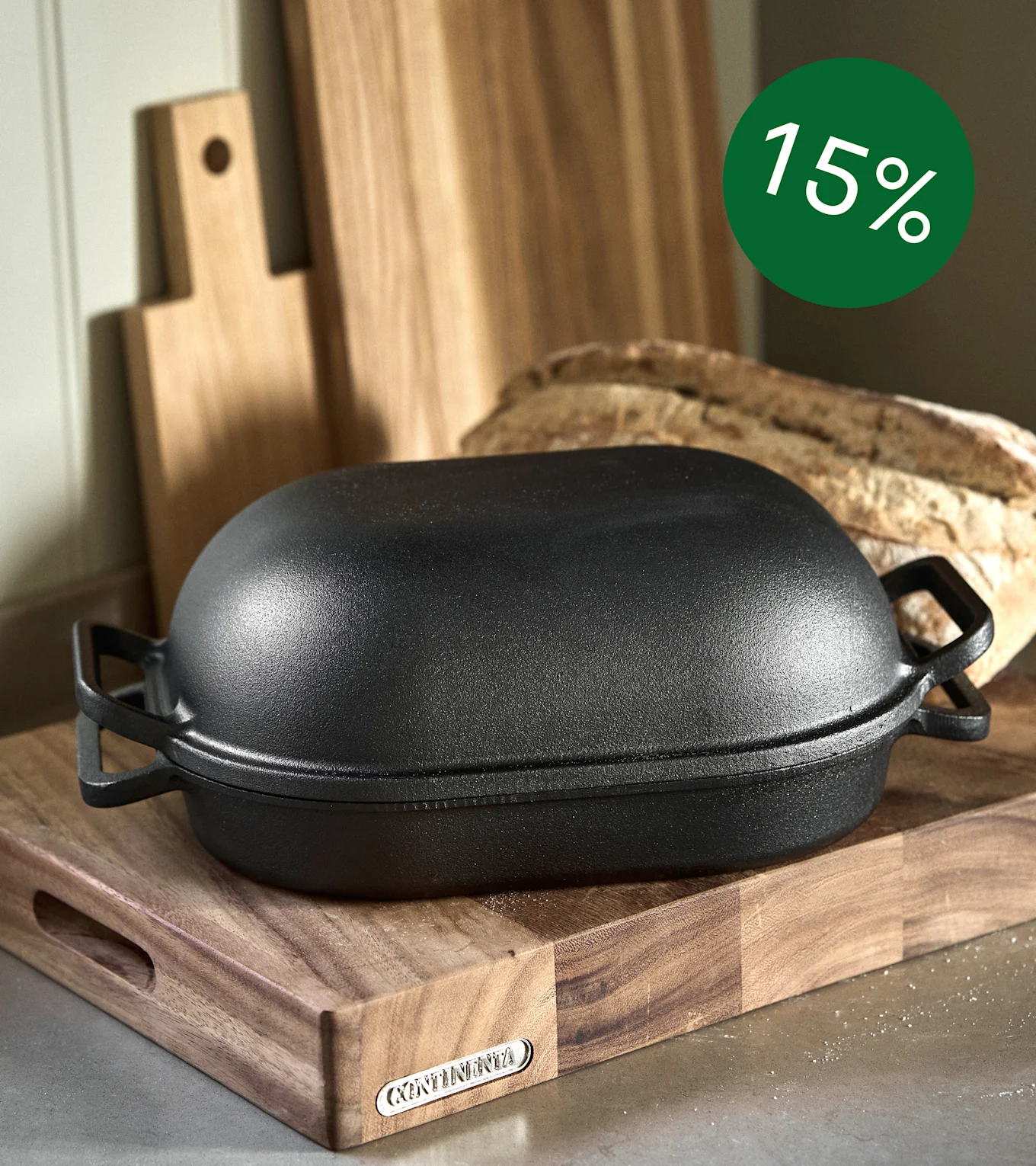 Black cast iron bread baker on a wooden board with bread and a 15% discount badge.