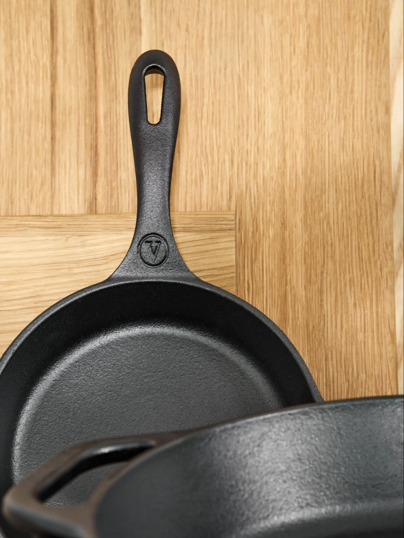 Cast iron pans require special car to keep them looking their best. Here you see a cast iron pan from Victoria leaning against a wooden cutting board. 