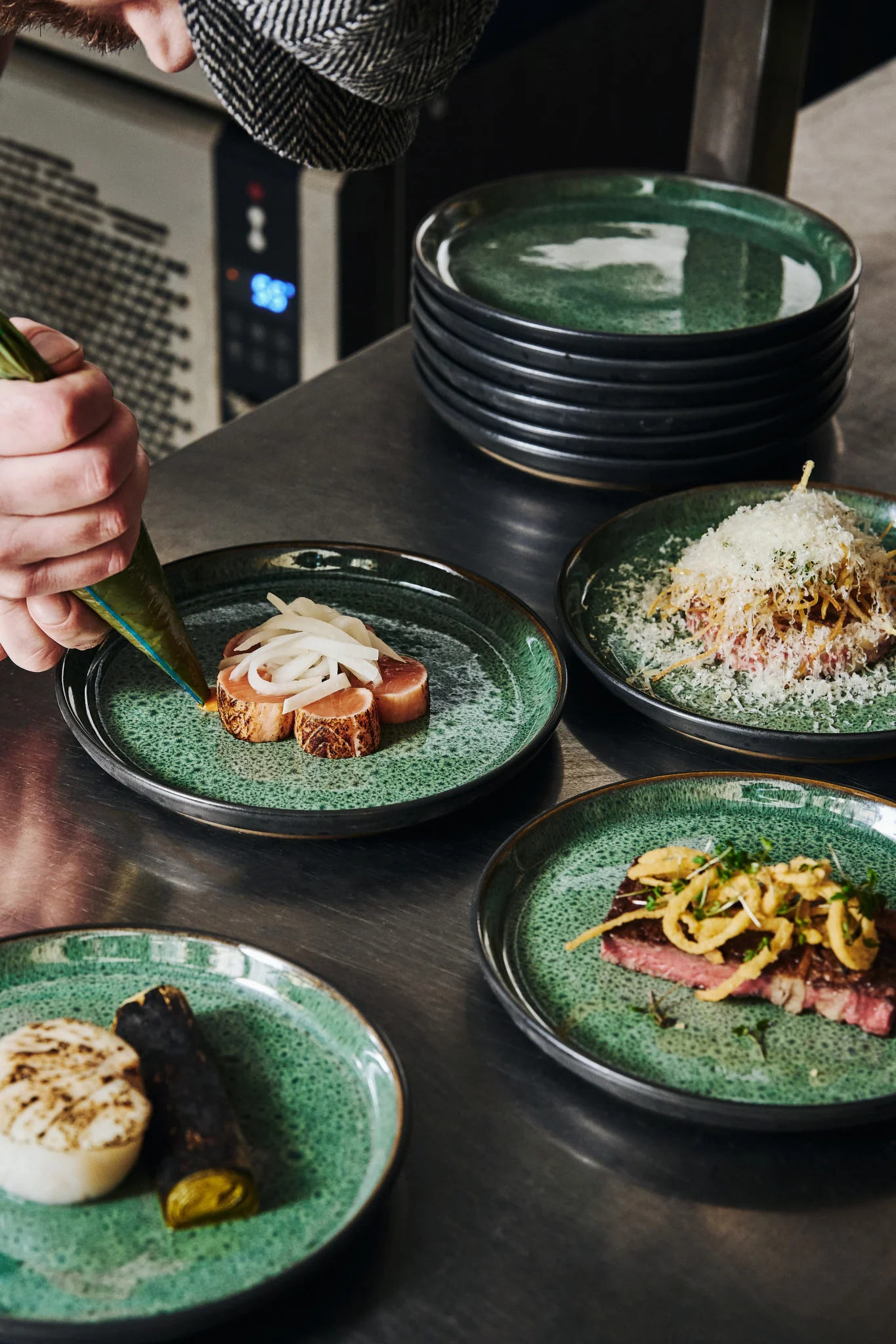 Hands pipe sauce onto a green plate in a professional kitchen. Discover how to plate food like a professional with our guide. 
