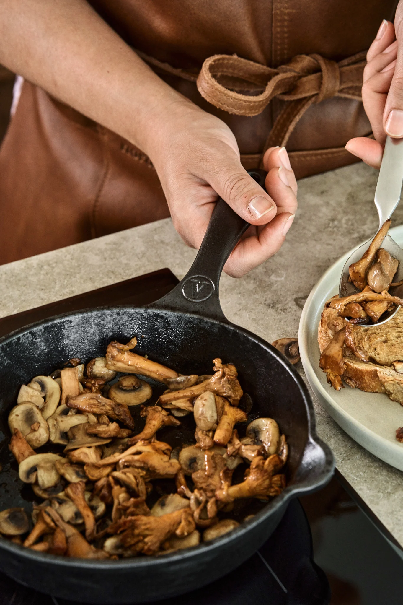 Someone fries chanterelle mushrooms in a cast iron pan on an induction hob.