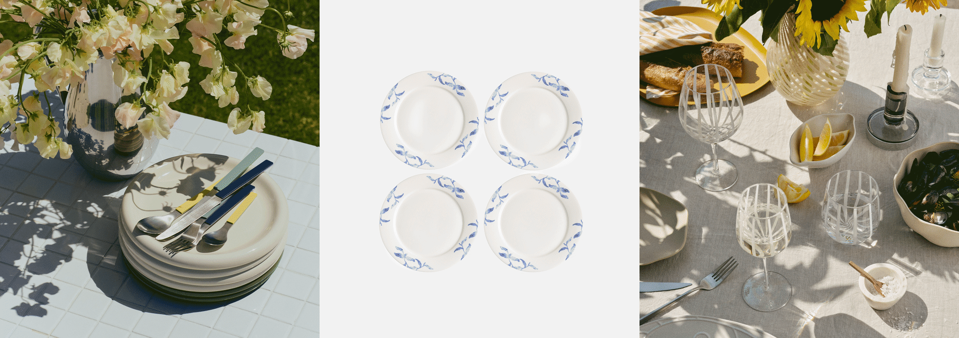 Outdoor summer dining scene: a vase of flowers and stacked plates, hands holding a bowl of strawberries, and a table set with food and drinks.