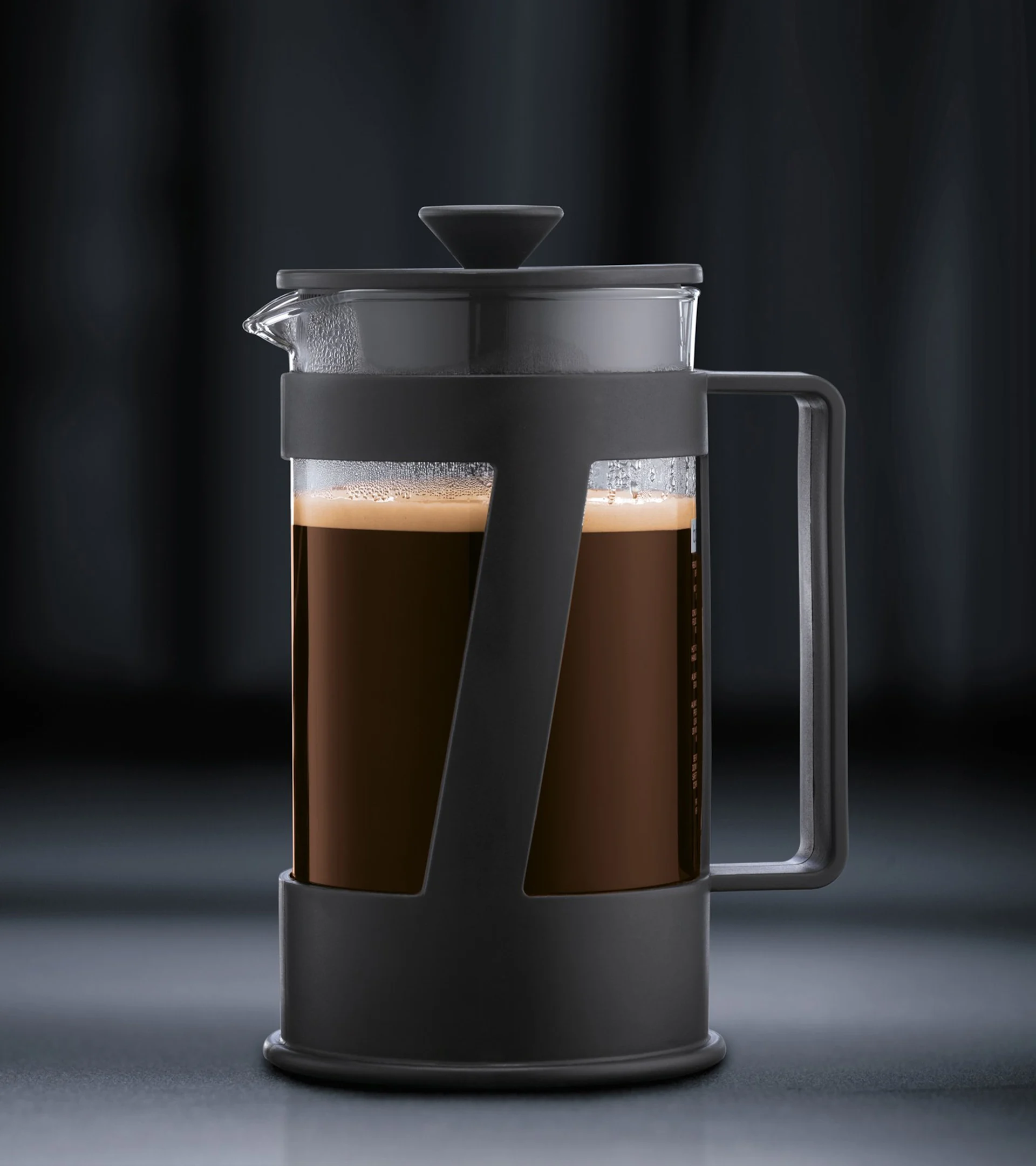 A silver KitchenAid espresso machine dispenses espresso into a glass of ice cream, creating an affogato. Another dessert is in the background.