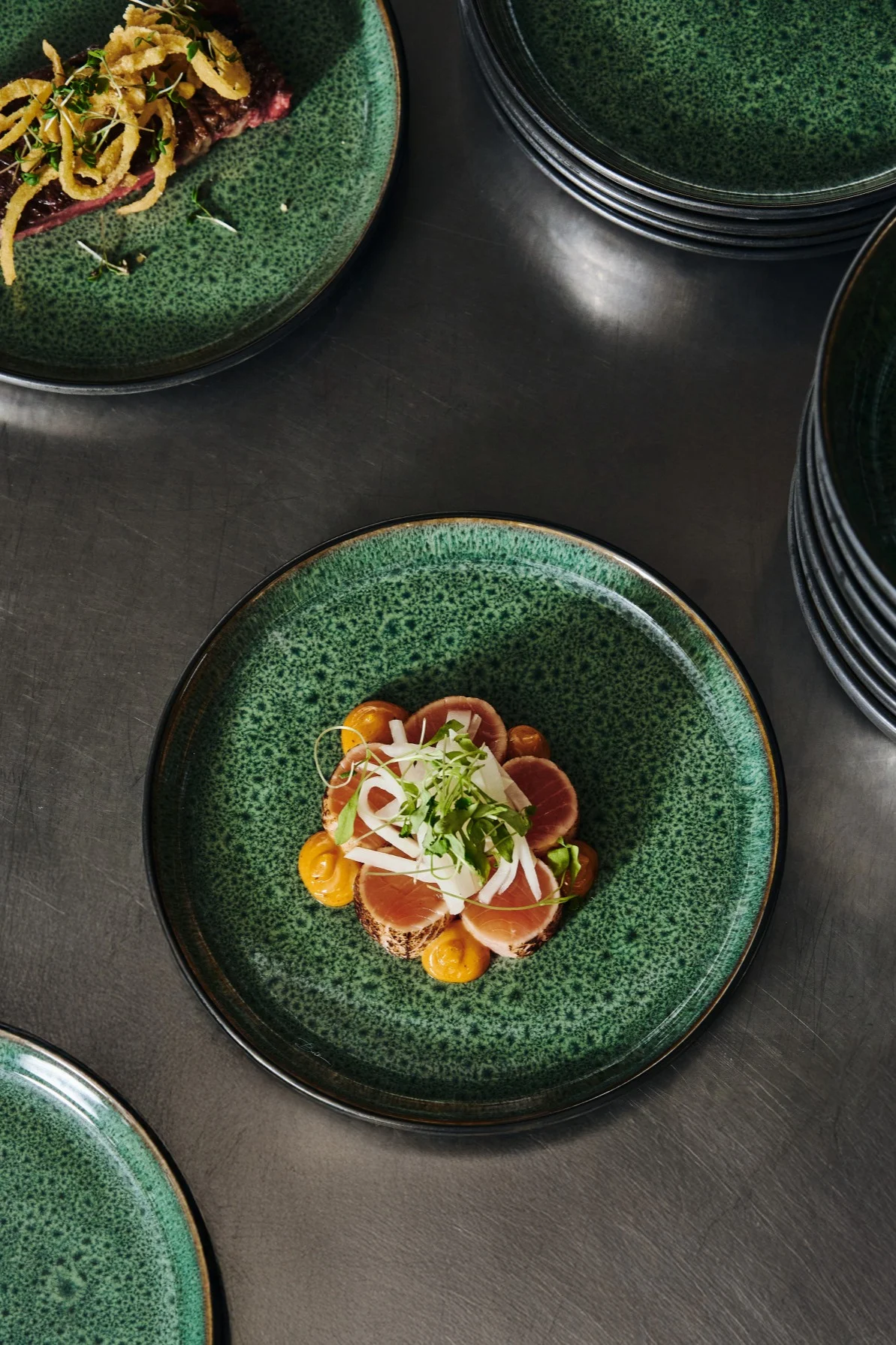 Plating food in odd numbers like you see here is one tip for plating like a professional. Here you see a plate orange salmon on a green plate from Bitz. 